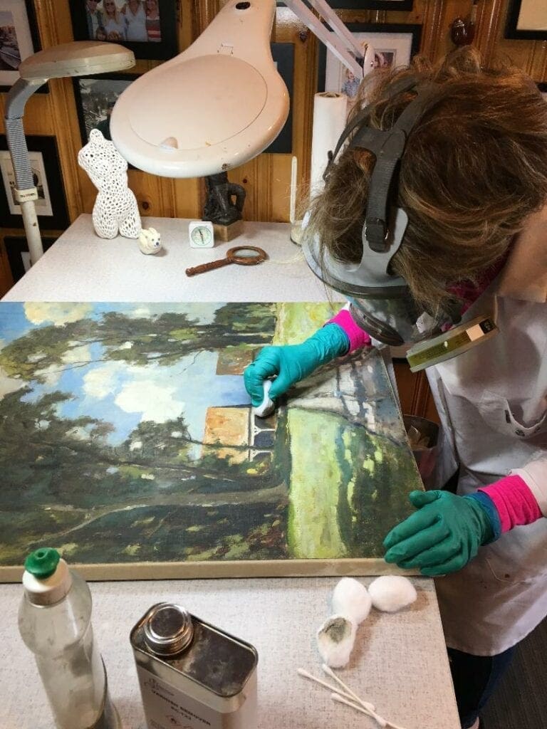A woman in gloves painting a picture on top of a table.